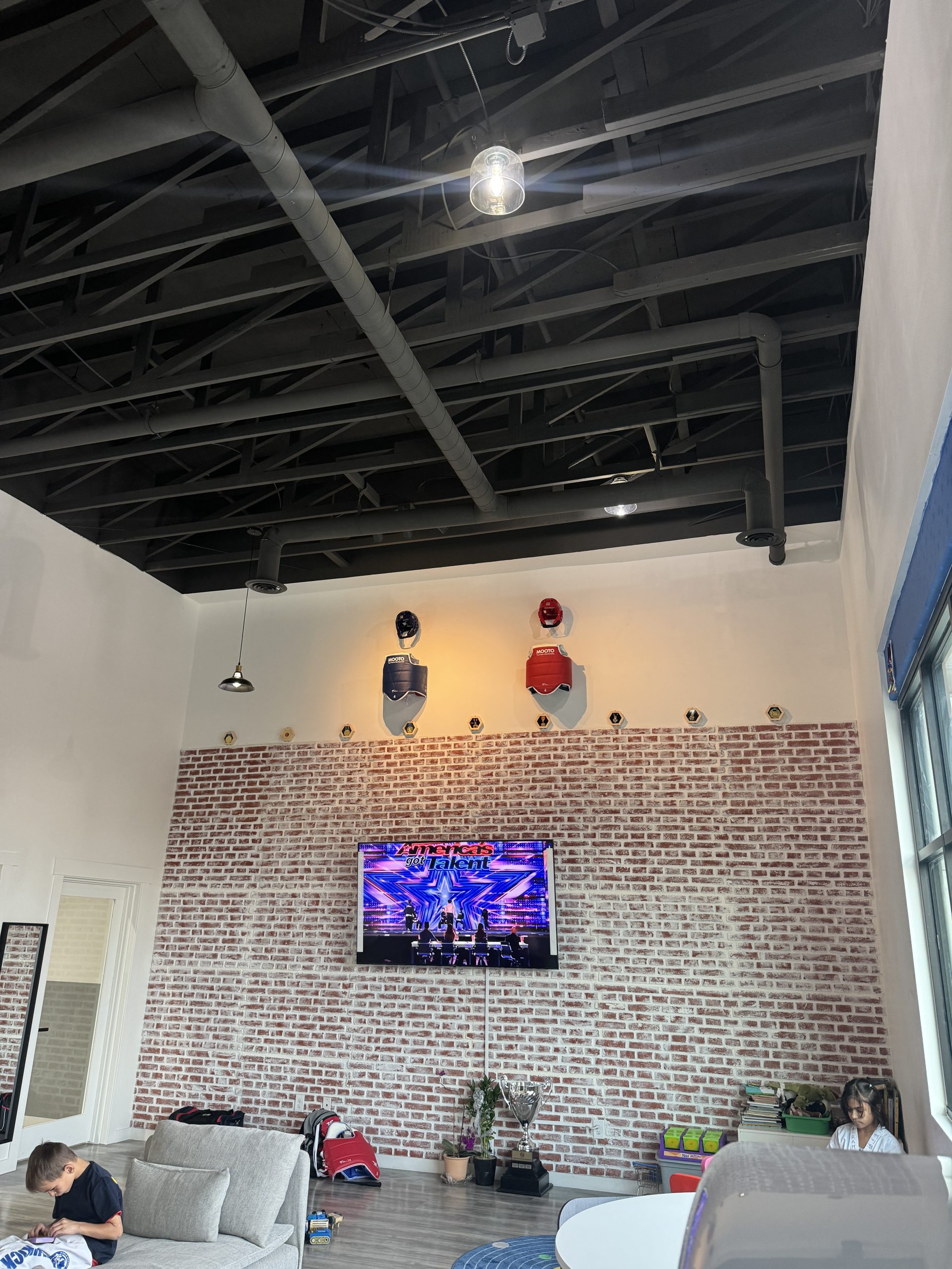 Commercial gym with black painted ceiling and brick accent wall